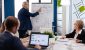 Confident man business coach giving flipchart presentation training diverse workers group at workshop, Serious speaker boss executive, business trainer explaining development strategy to motivated mixed race employees.