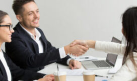 Friendly satisfied partners handshaking at group meeting thanking for successful teamwork, smiling millennial businessman shaking hand greeting businesswoman, respect or making contract deal concept
