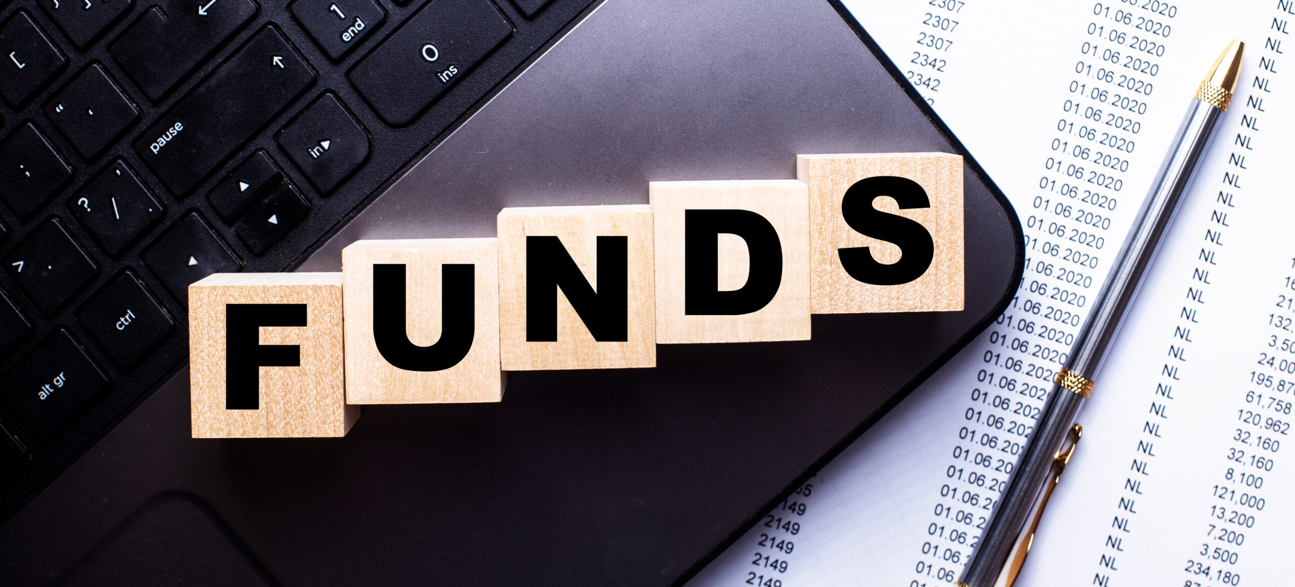 On the laptop, on wooden cubes near the pen, the word FUNDS is written.