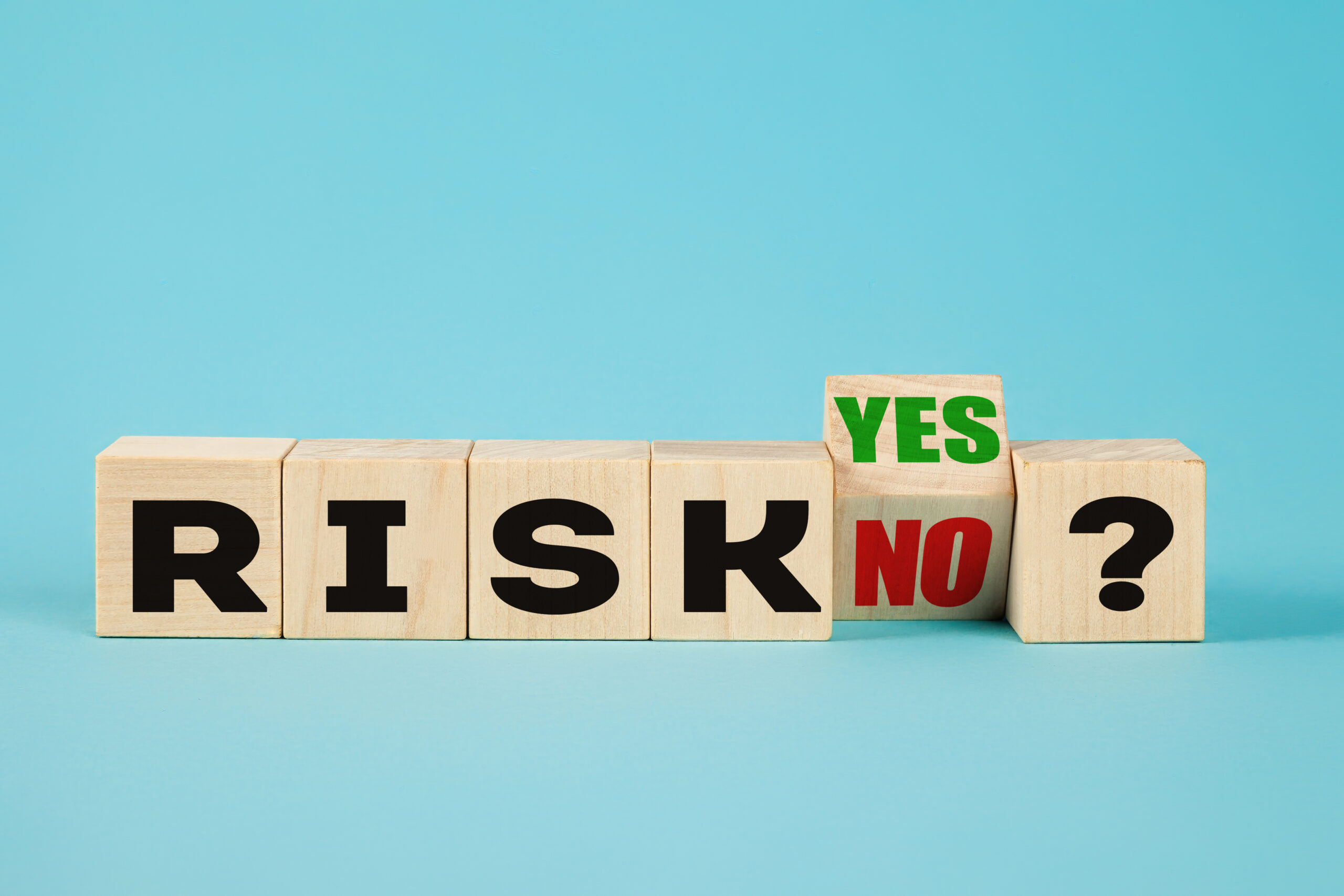 Risk symbol. A wooden cube with the word risk yes or no representing high or low risk. Business and risk concept.