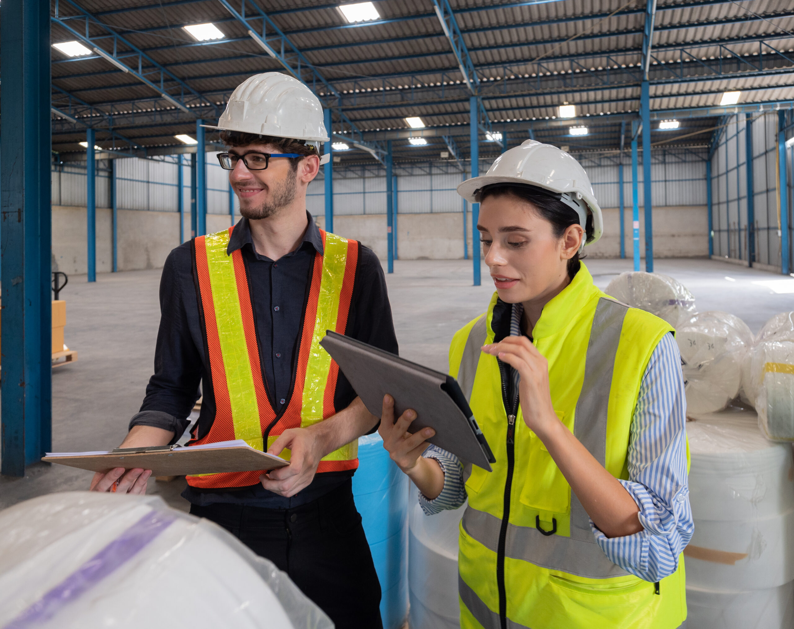 Two warehouse staff in uniform are checking the quality and stoc