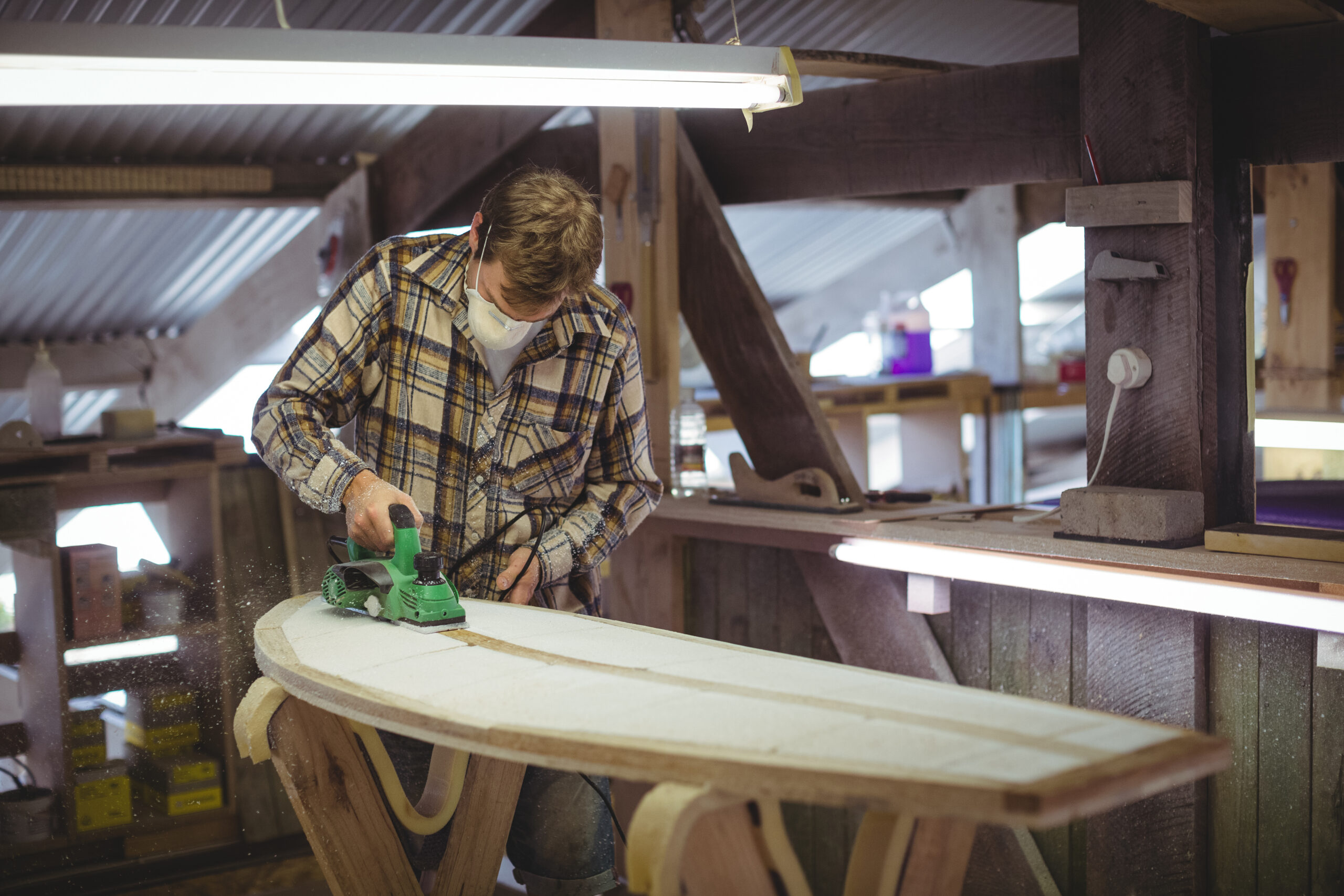 Man using modified planer in the surfboard workshop